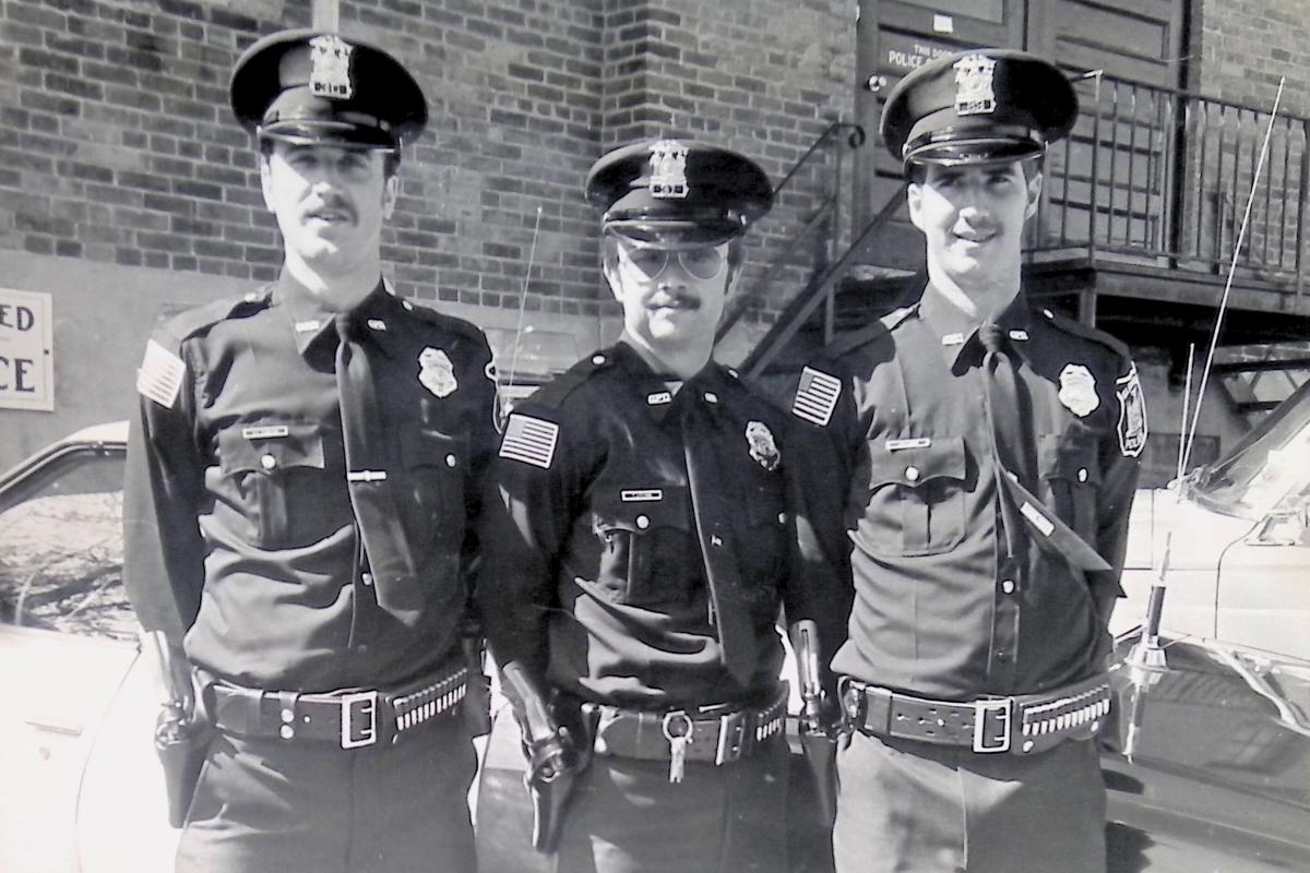 three police officers standing in front of a building
