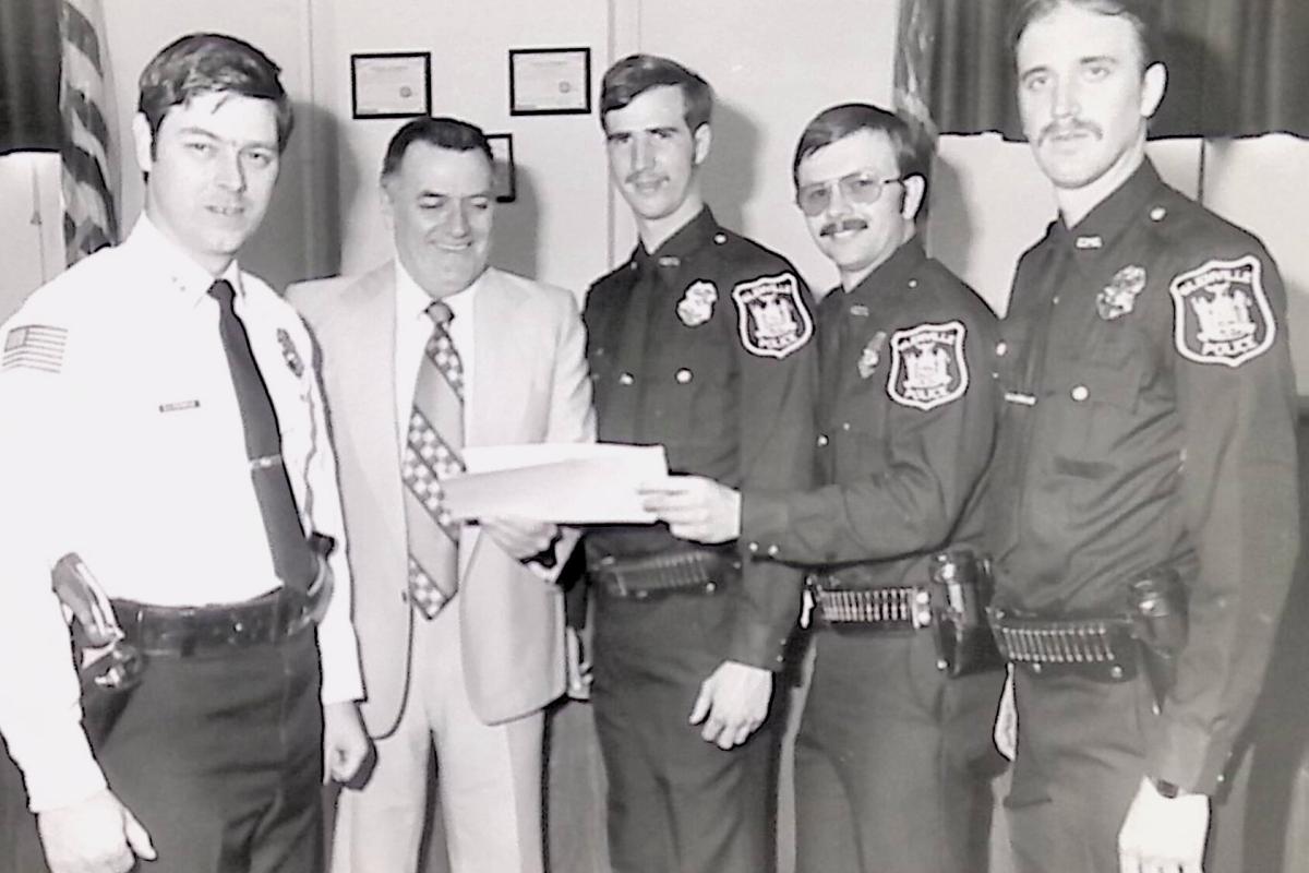 5 police officers pose inside an office